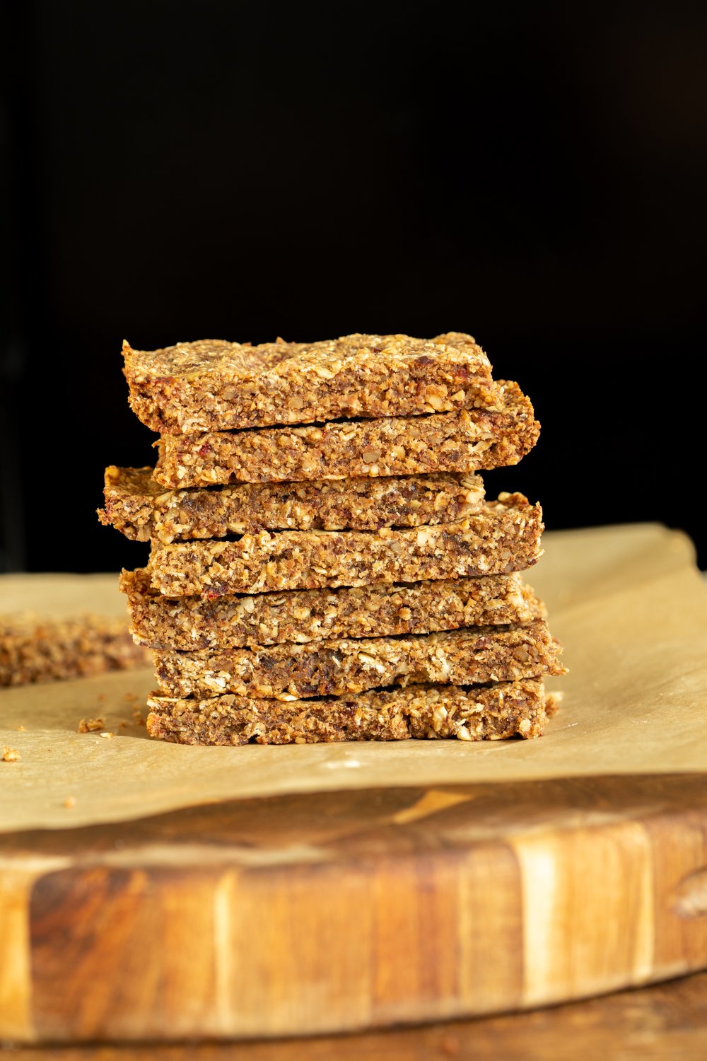 vegan granola bars  a stack of vegan caramelized banana & nut granola bars against a black background