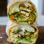 curried tofu banh mi wrapped in butcher paper and sliced in half