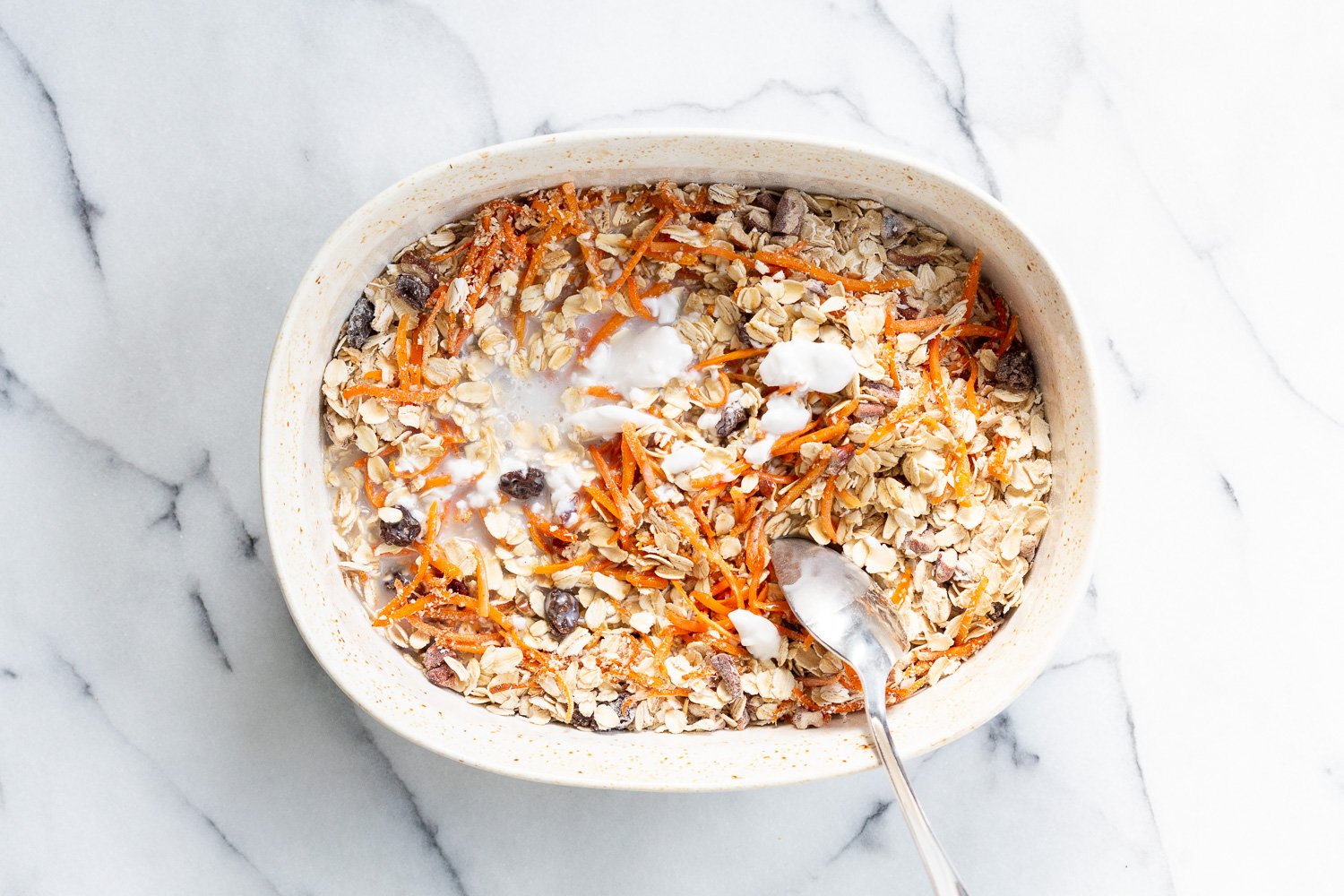 Non Dairy milk mixed with dry ingredients for Our Vegan Carrot Cake Baked Oatmeal in a baking dish