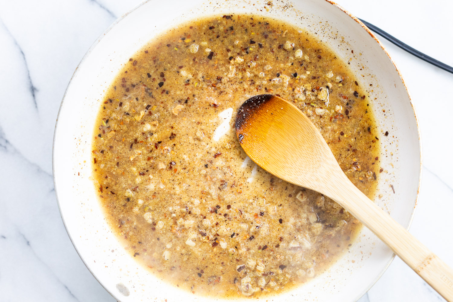 Pepper, vegan parmesan and broth for our vegan cacio e pepe in a white skillet