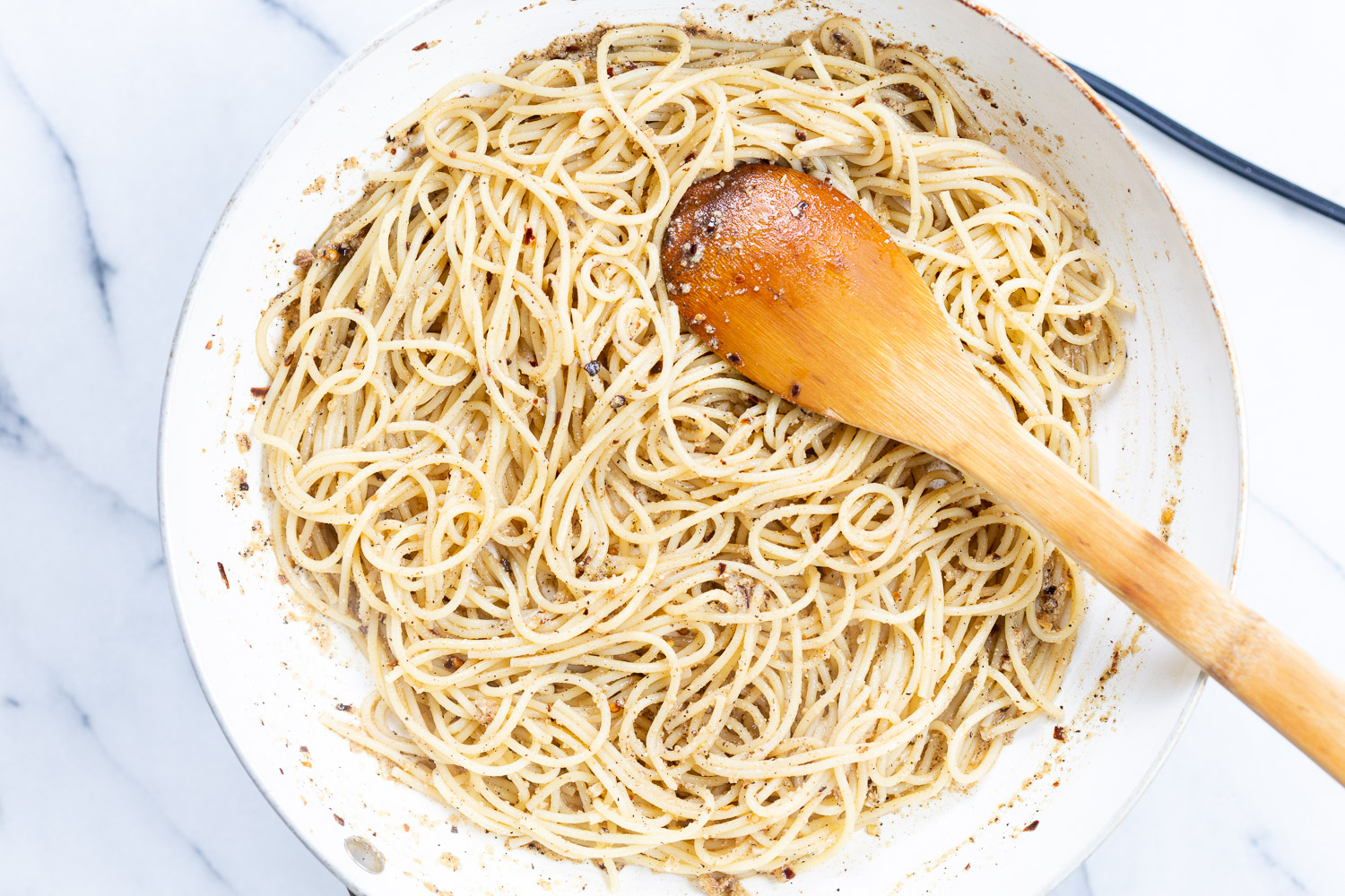 Spaghetti for our Cacio e Pepe in a white skillet