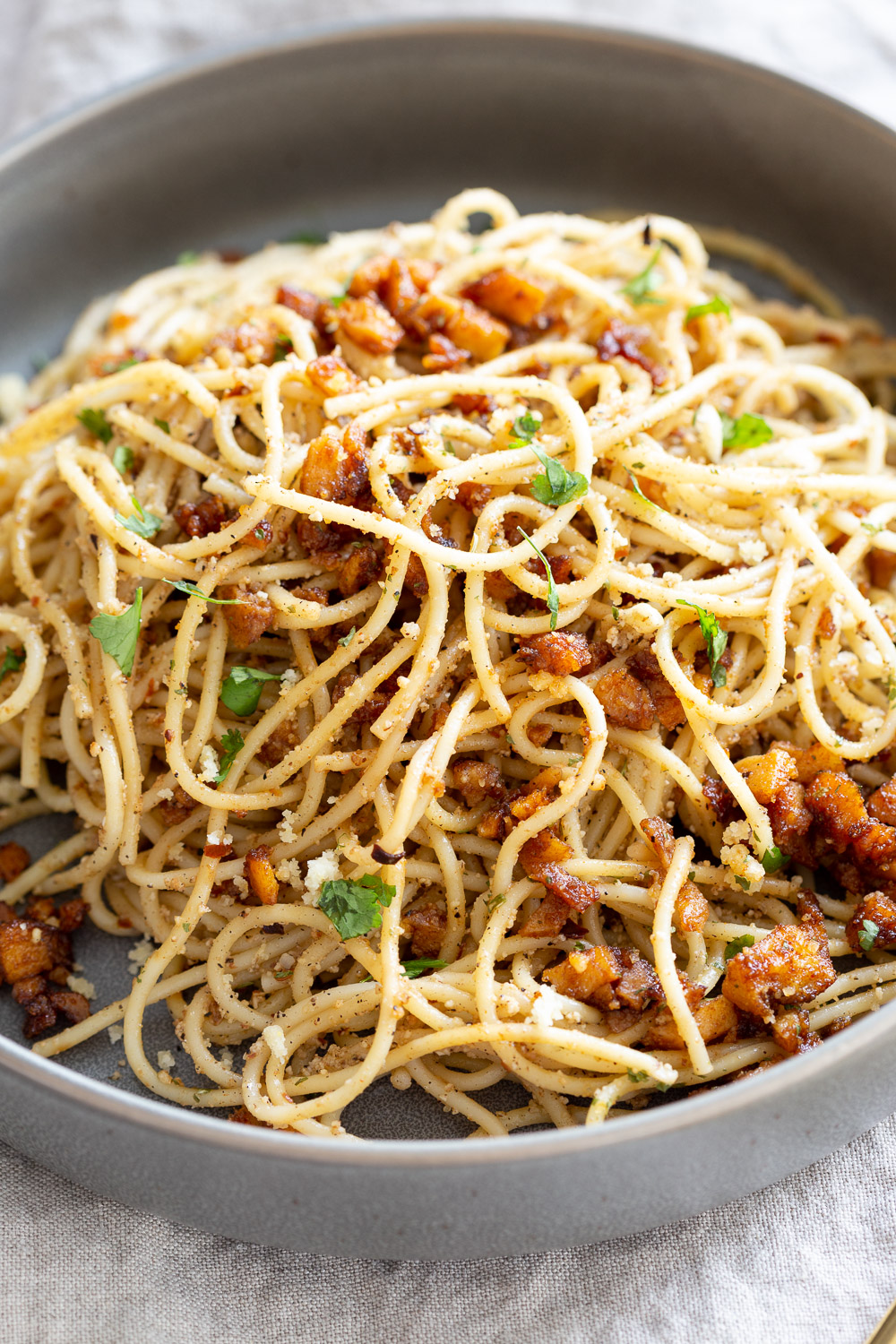 Vegan Cacio e Pepe with Smoky Balsamic Roasted Chickpea tofu in a grey bowl