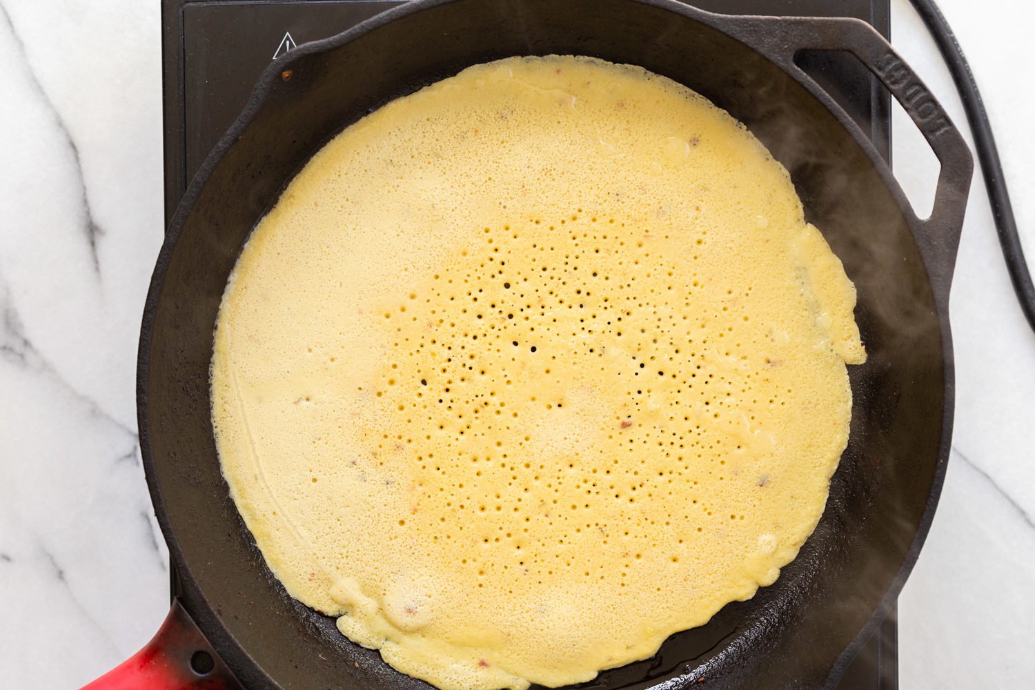 Socca cooking in cast iron skillet