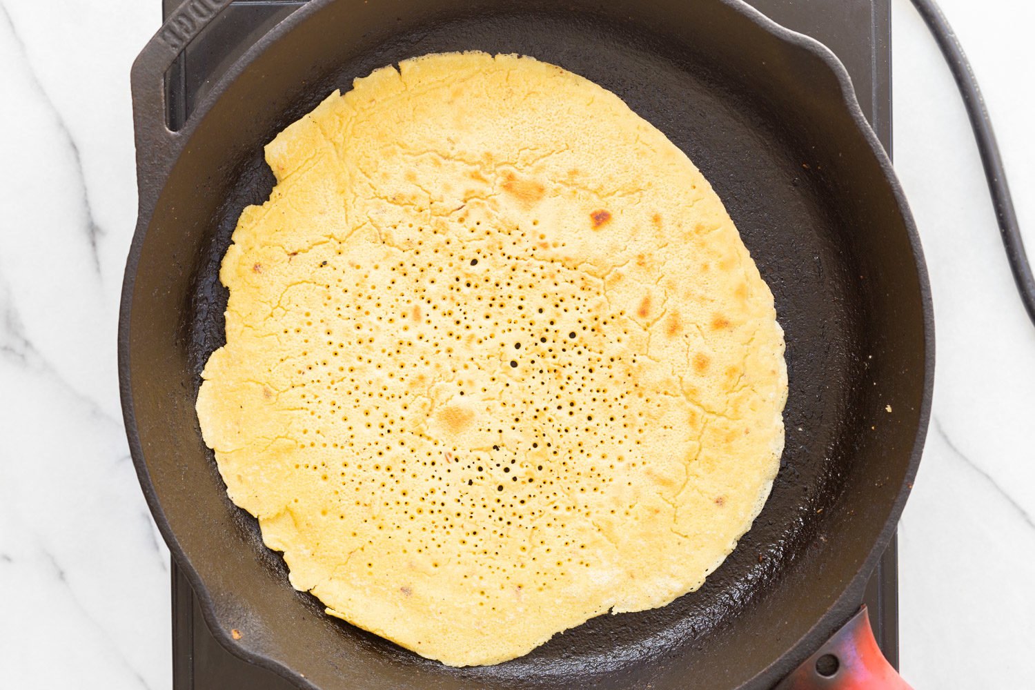 Socca cooking in cast iron skillet