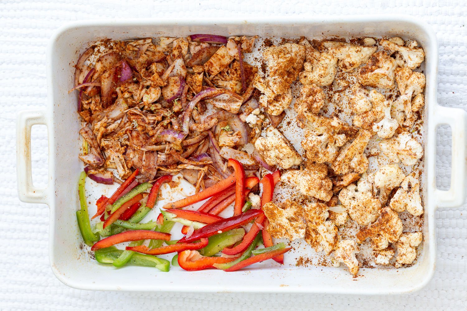Chili Lime Roasted Veggies & Jackfruit mixed with taco spice and lime and spread on a white baking dish