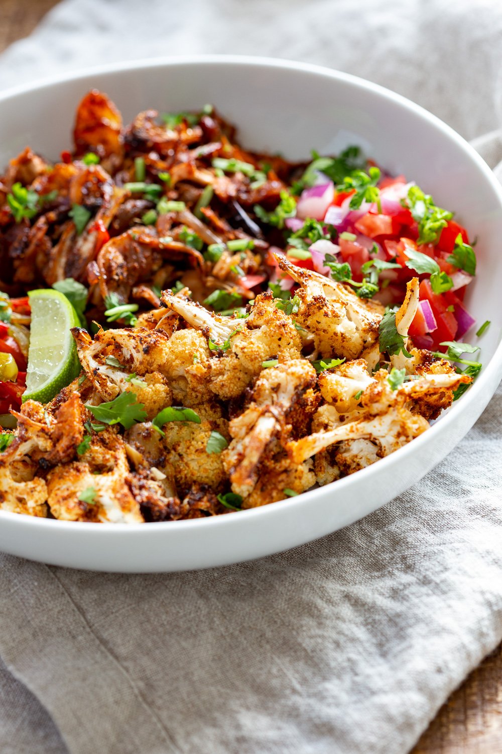 Chili Lime Roasted Veggies & Jackfruit in a White Bowl to be drizzled with jalapeno cream sauce