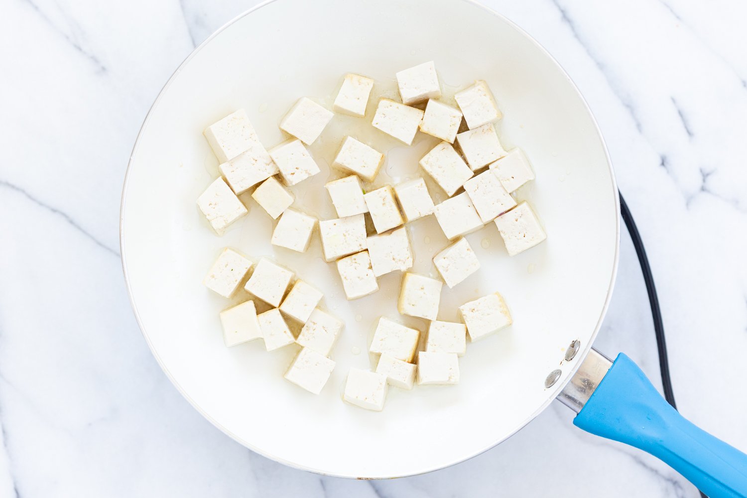 Tofu panfried in a white skillet for our Vegan Paneer Lababdar