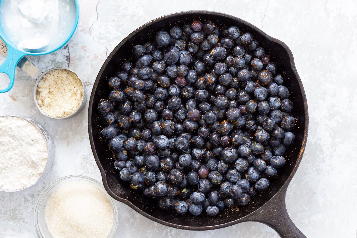 Blueberries sugar and lemon zest in cast iron skillet for our Vegan Blueberry Cobbler