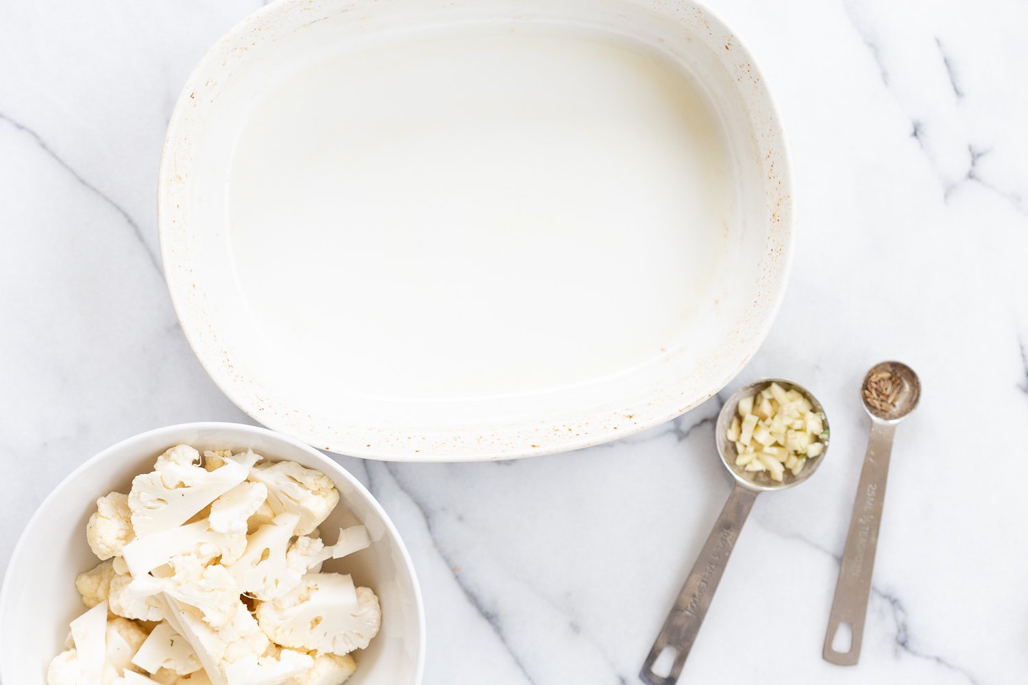 Cauliflower and garlic in a bowl for our Vegan Cauliflower Pea Curry Gobi Matar
