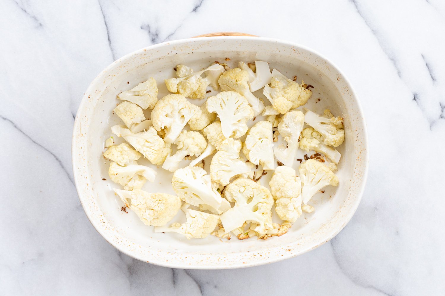 Baked cauliflower in a baking dish for our Vegan Cauliflower Pea Curry