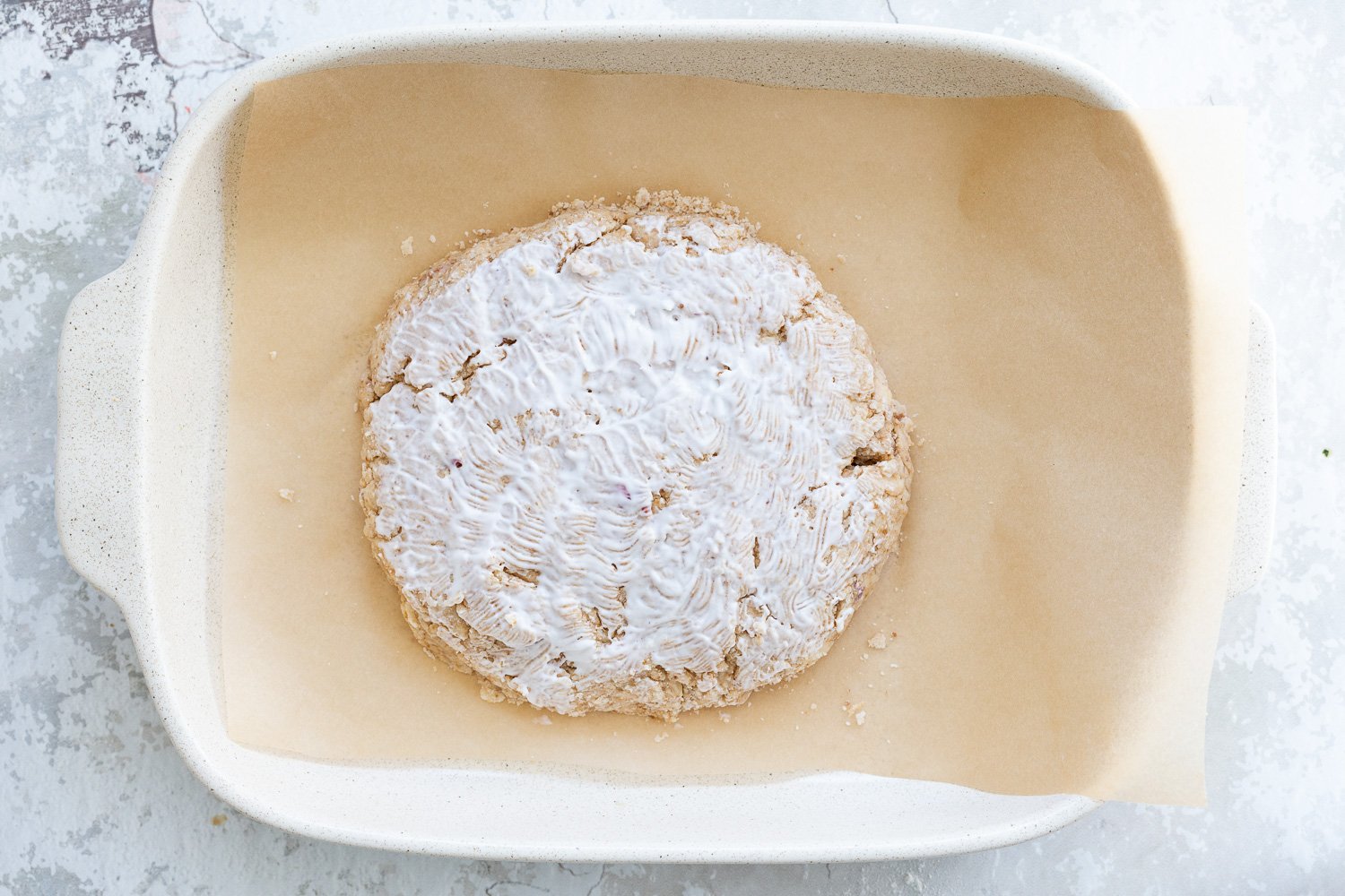 Coconut cream bushed on Dough for our Vegan Churro Scones in a parchment lined baking sheet.