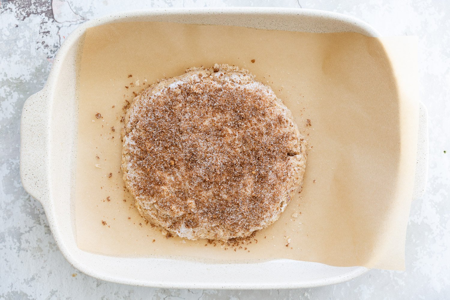 Cinnamon sugar topped Dough for our Vegan Churro Scones in a parchment lined baking sheet.