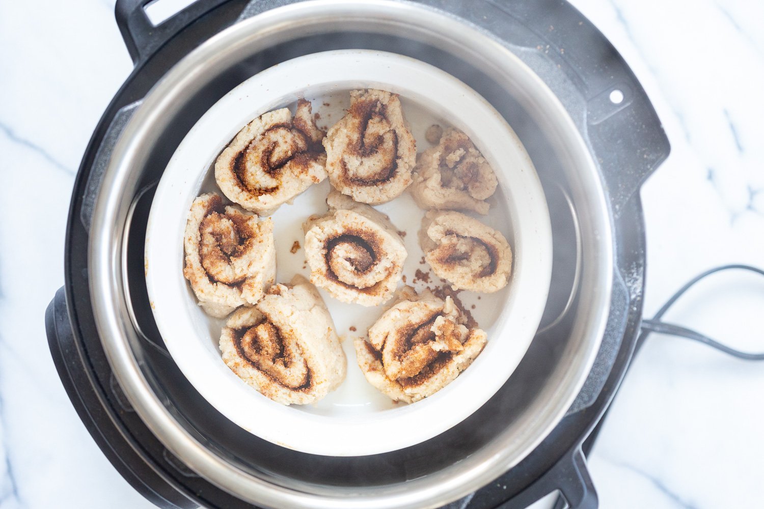 Our Vegan Gluten free Cinnamon Rolls dough sliced and placed in stoneware ready to steam in Instant Pot