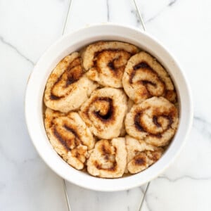 Our Vegan Gluten free Cinnamon rolls in a stoneware dish on marble