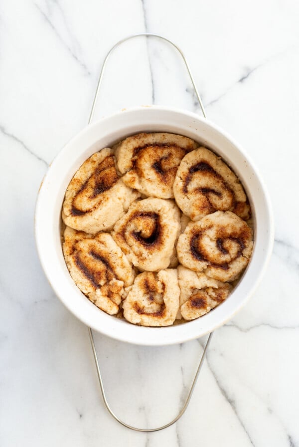 Our Vegan Gluten free Cinnamon rolls in a stoneware dish on marble