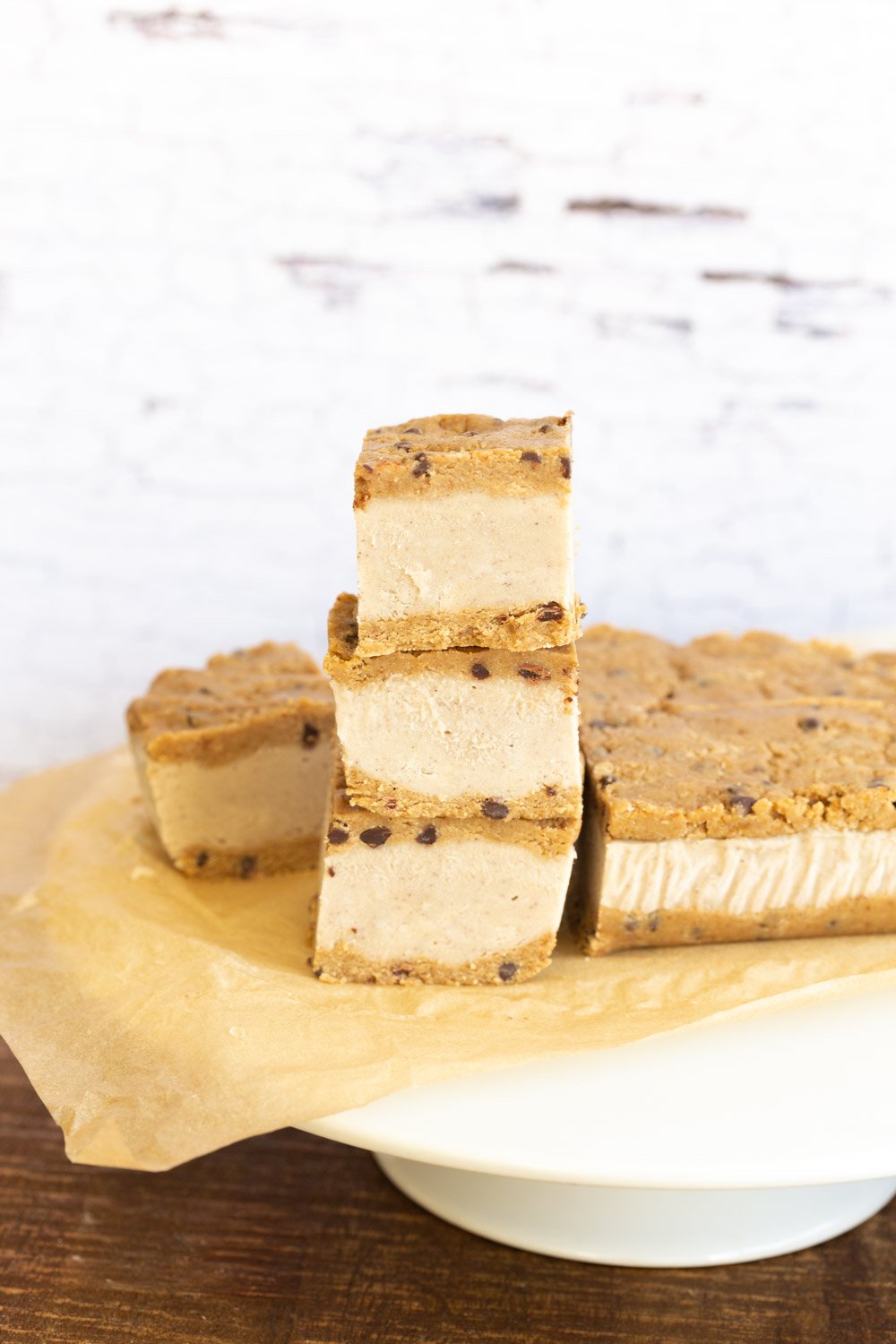 Vegan Cookie Dough Ice Cream Sandwiches stacked on a white cake stand