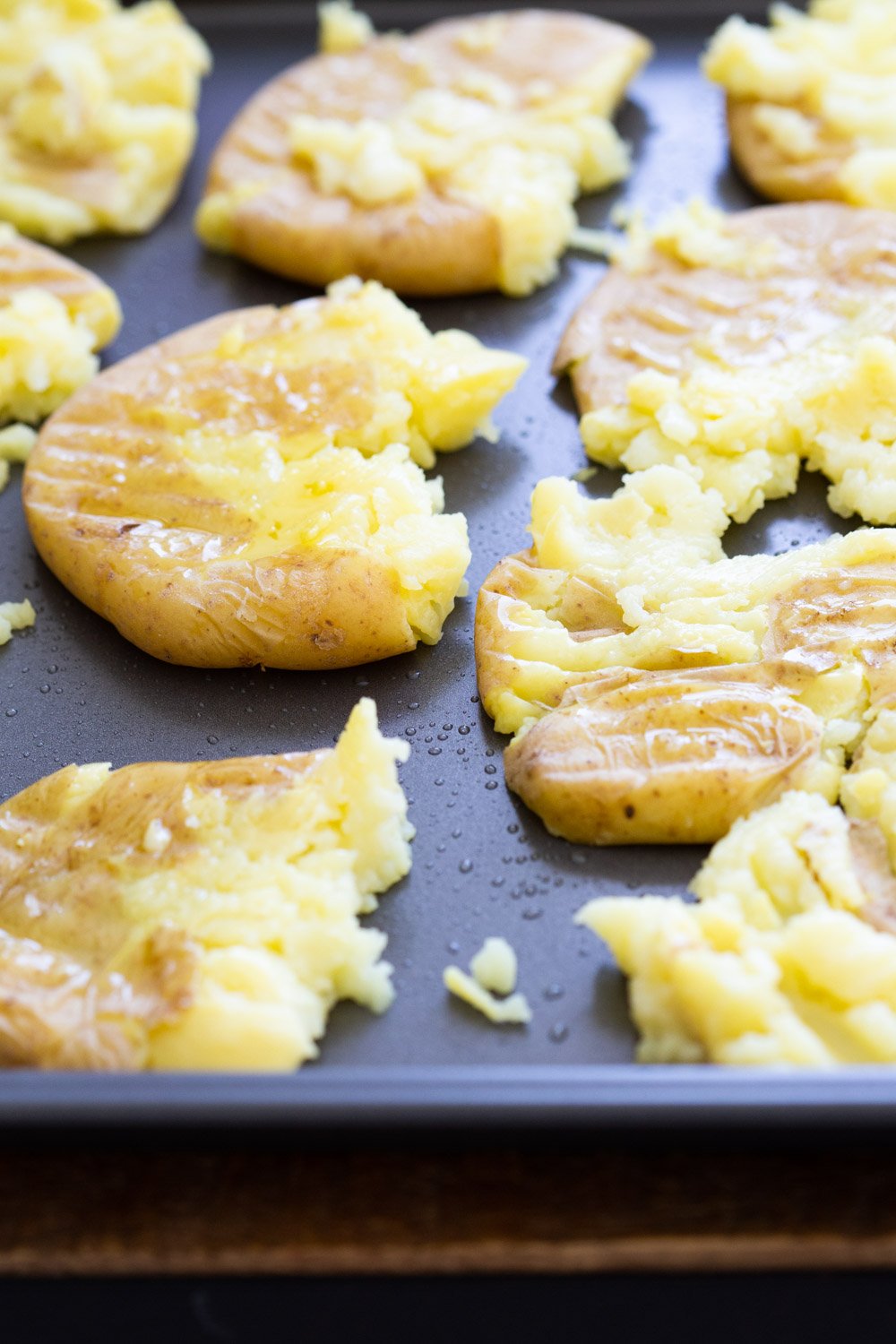 Cooked potatoes pressed on a baking sheet for our Crispy Vegan Smashed Potatoes with Chimichurri.