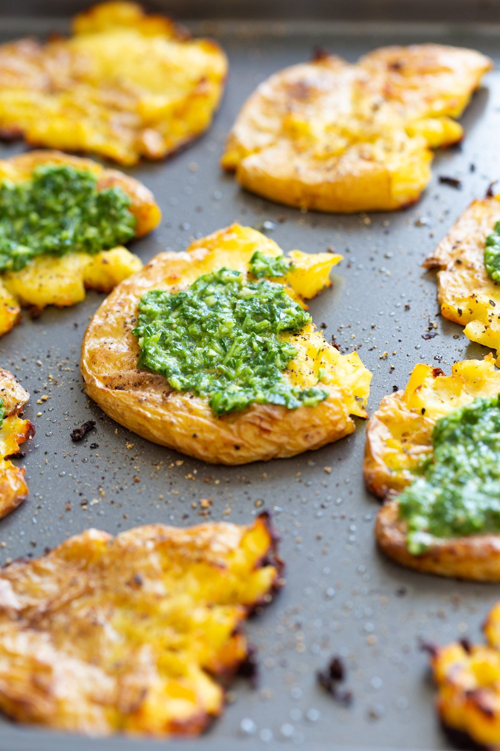 Vegan Smashed Potatoes with Chimichurri Sauce on a Grey Baking sheet