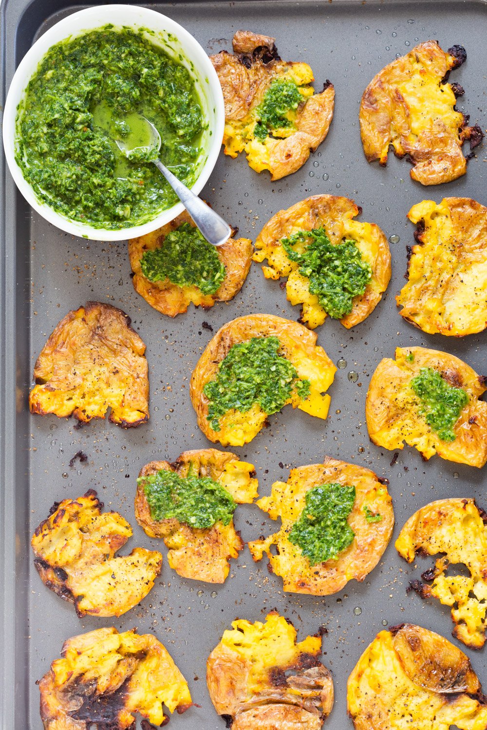 Vegan Smashed Potatoes with Chimichurri Sauce on a Grey Baking sheet