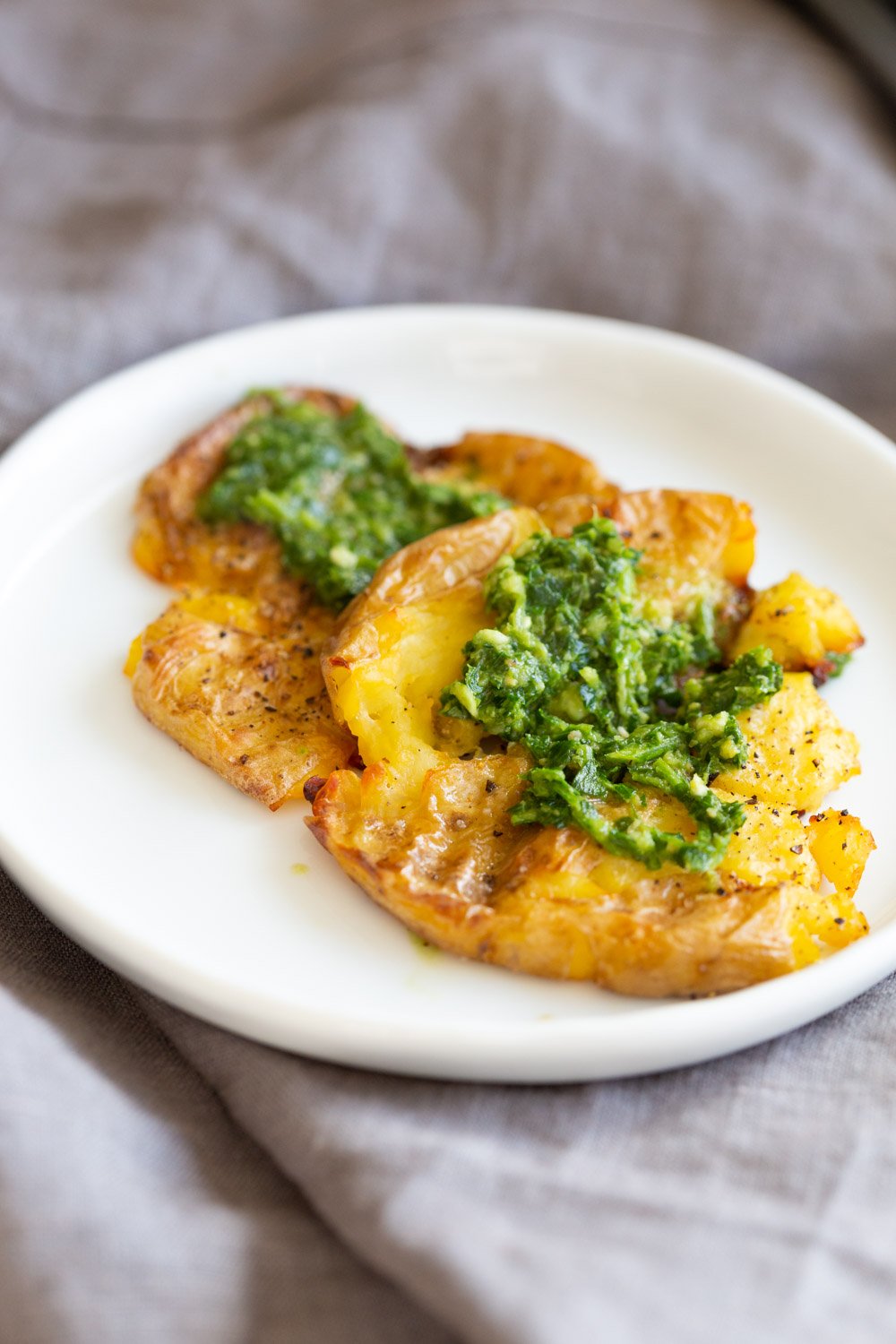 Vegan Smashed Potatoes with Chimichurri Sauce on a white plate