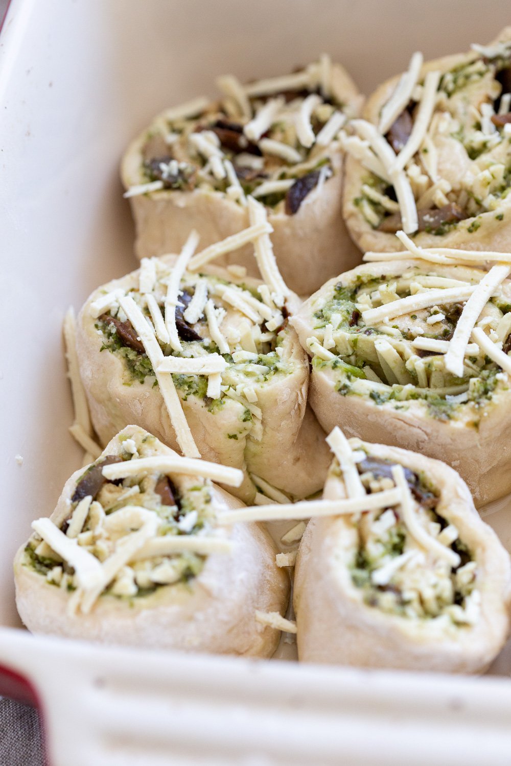 pizza rolls recipe Pesto Pizza rolls unbaked in a white ceramic baking dish