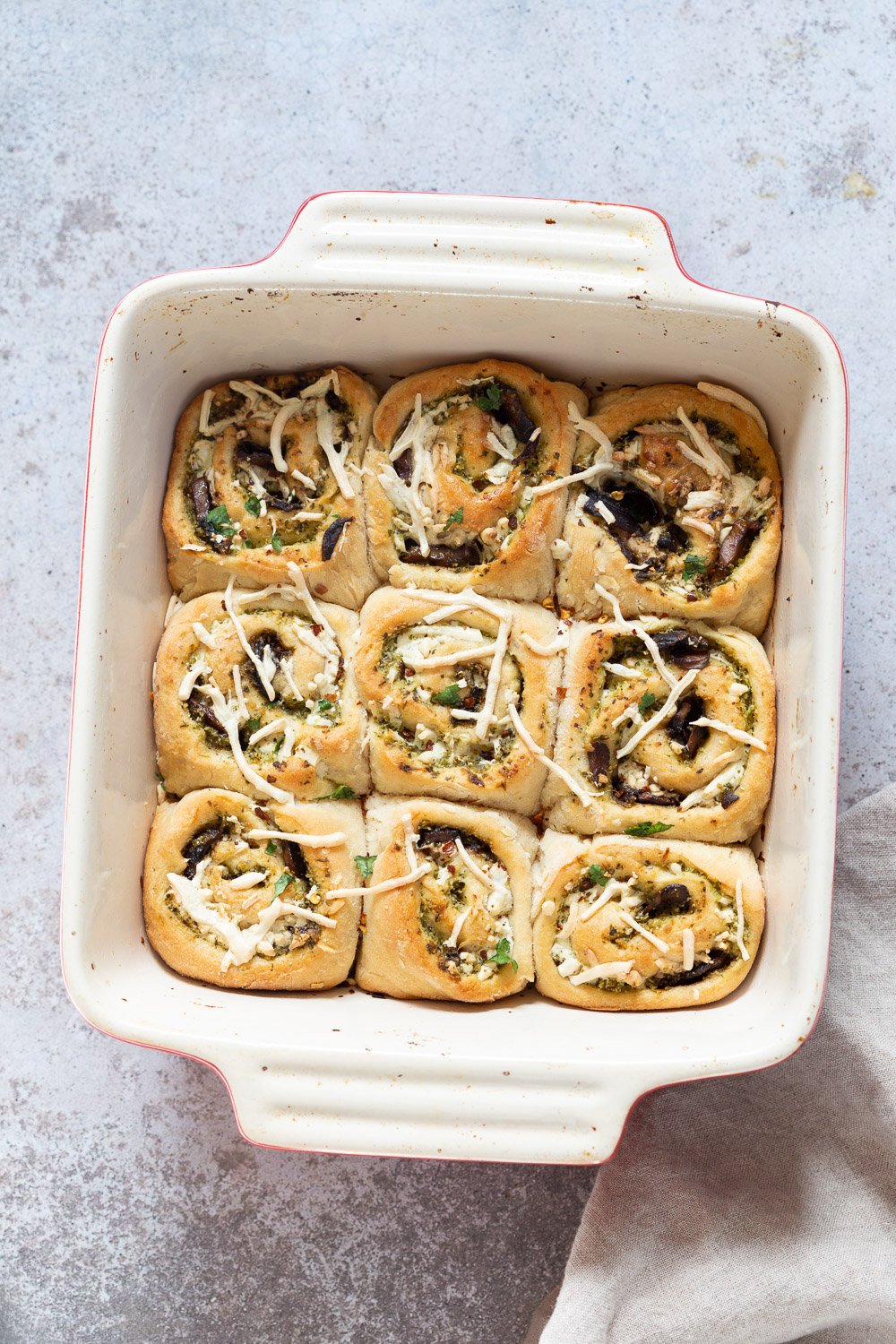 pizza rolls recipe overhead shot of vegan Pesto Pizza rolls in a ceramic baking dish