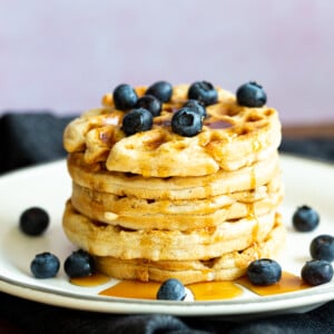 Our Easy Vegan Waffles stacked on a white plate over black napkin