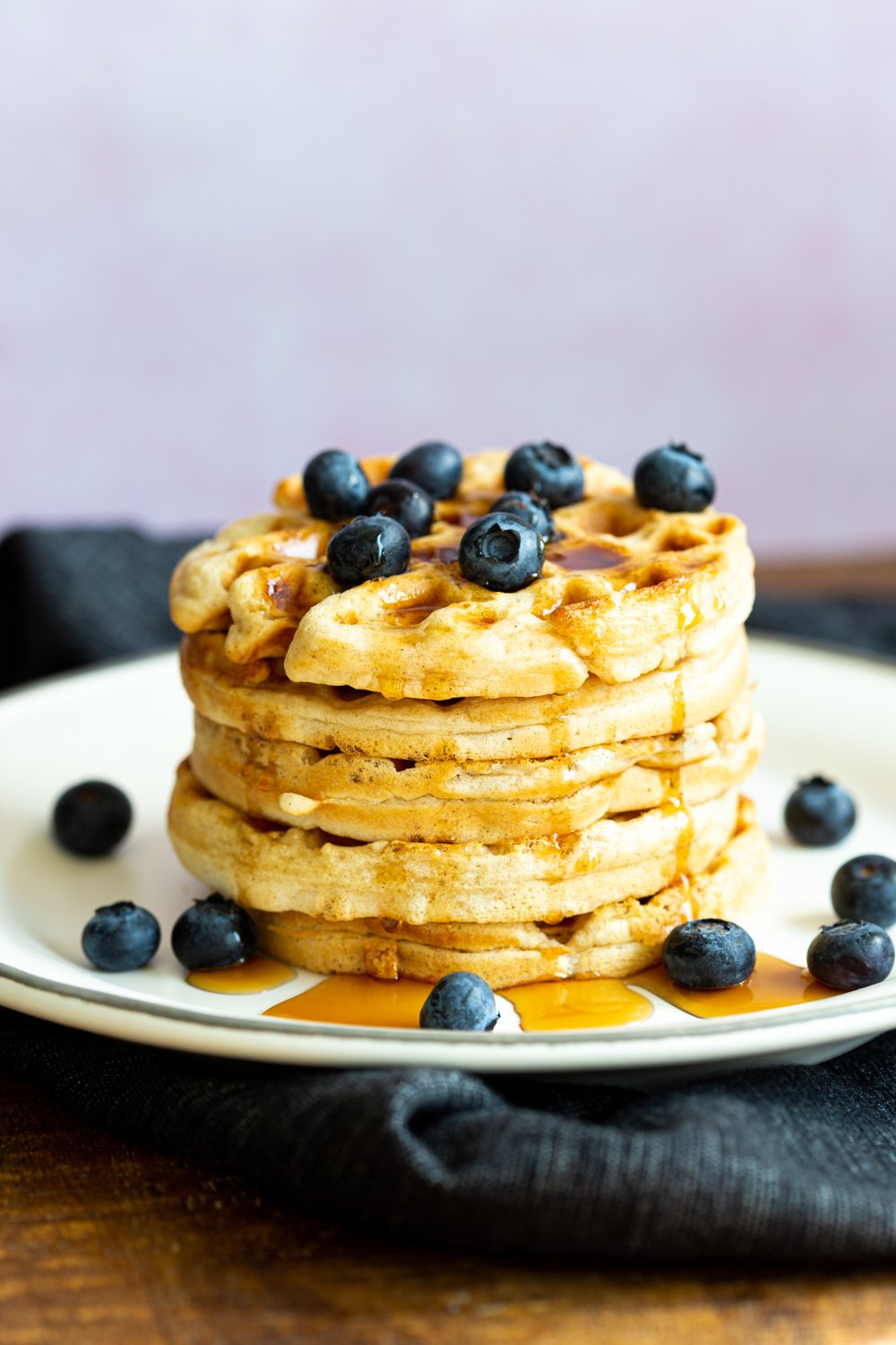 Our Easy Vegan Waffles stacked on a white plate over black napkin