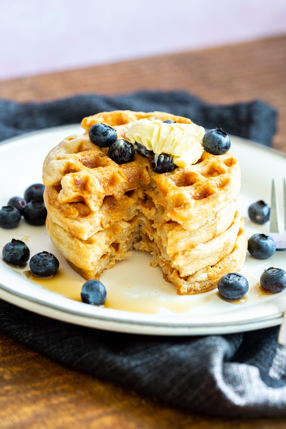 Our Easy Vegan Waffles stacked on a white plate over black napkin