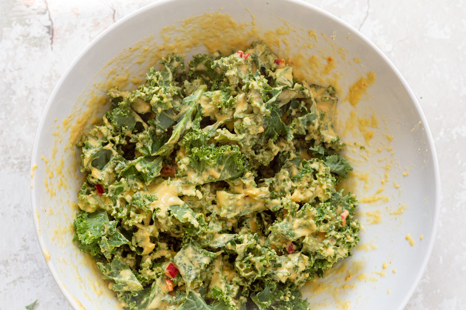 Kale leaves coated in batter, in a white bowl