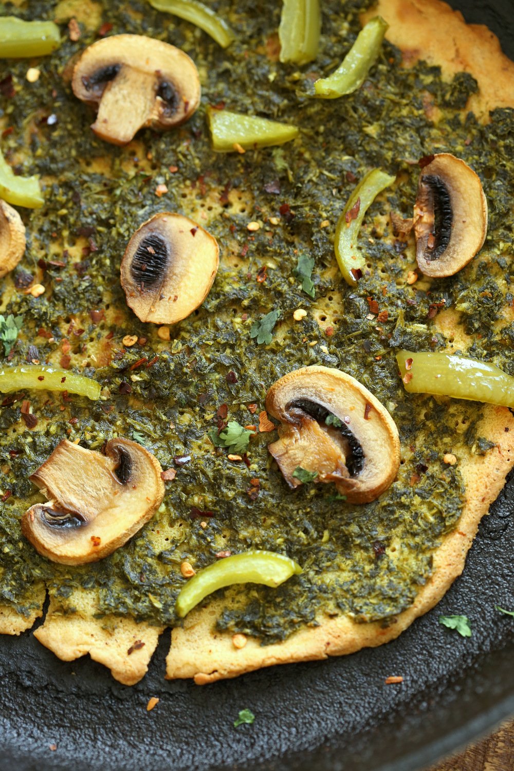 Socca Pizza with pesto and mushrooms on cast iron skillet