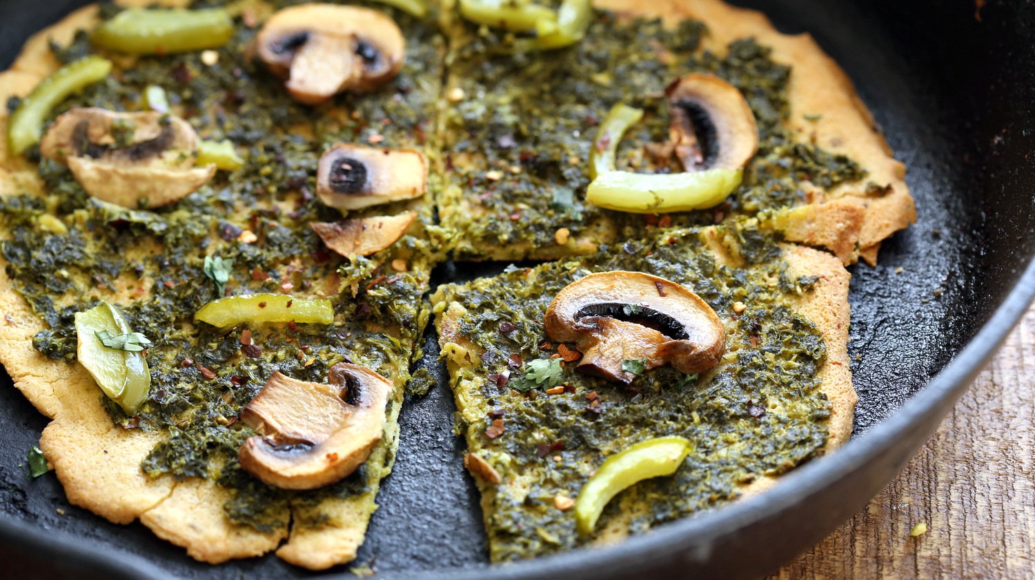Socca Pizza with pesto and mushrooms on cast iron skillet