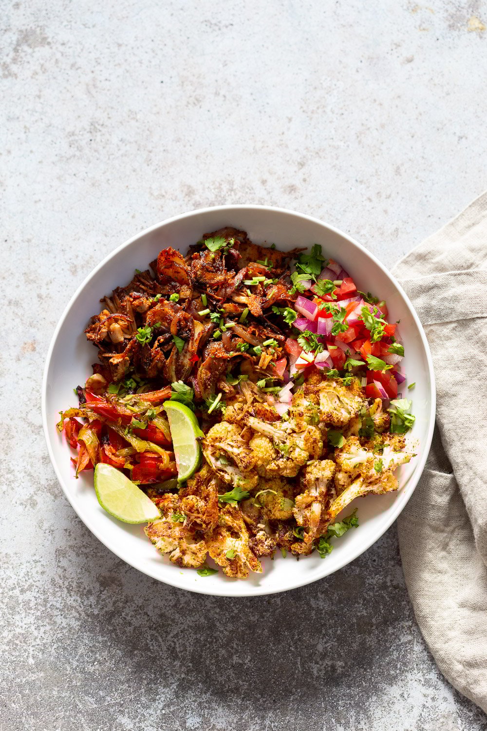 Chili Lime Roasted Veggies & Jackfruit in a White Bowl to be drizzled with jalapeno cream sauce