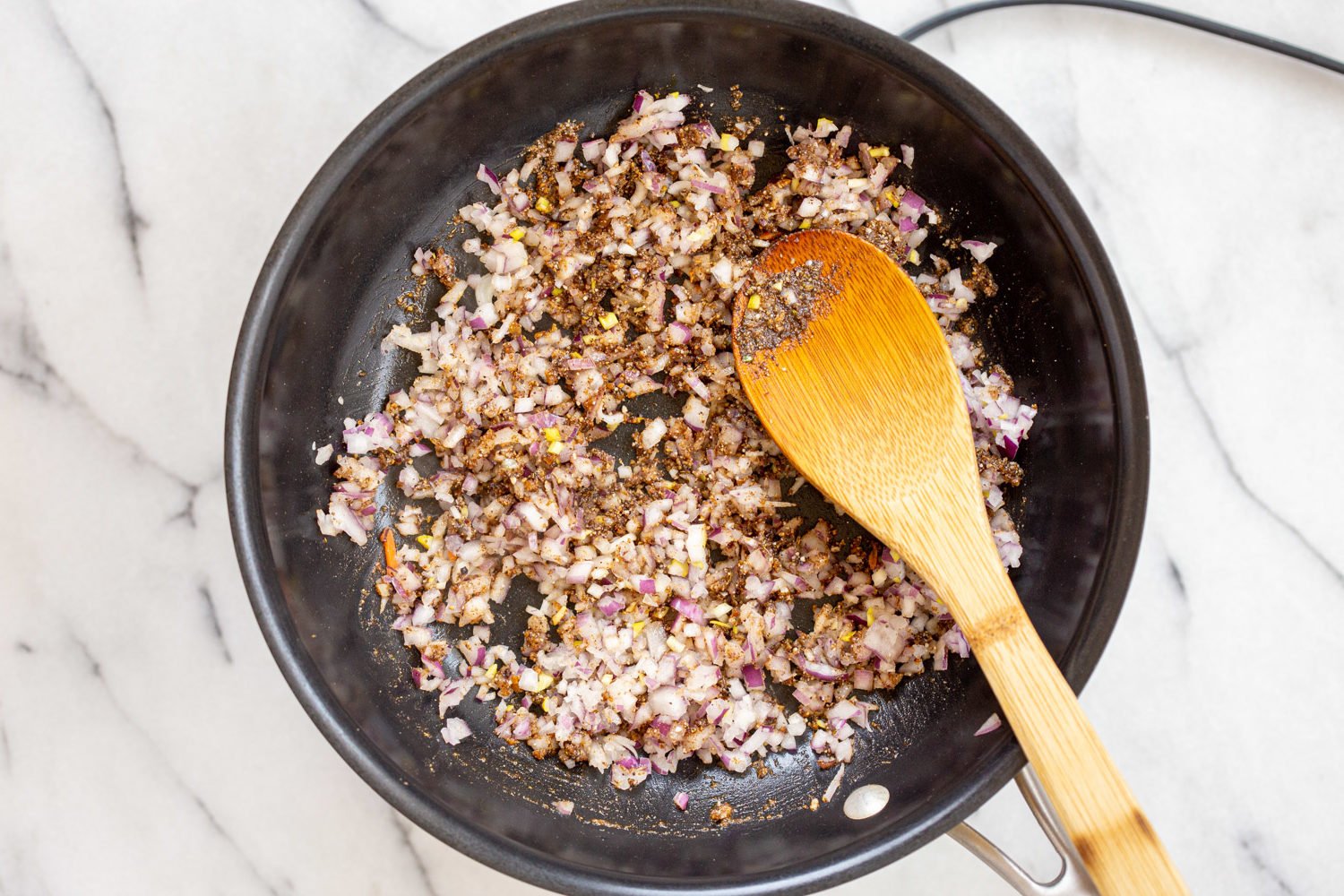 spices and onion for our Vegan Keema Madras on a black skillet