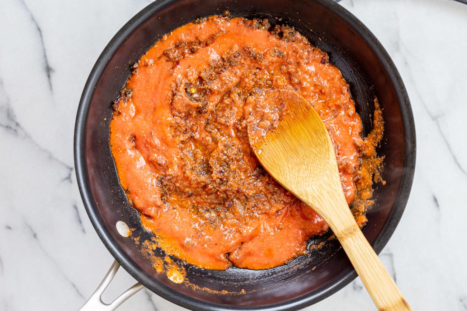 Tomato puree for our Vegan Keema Madras on a black skillet