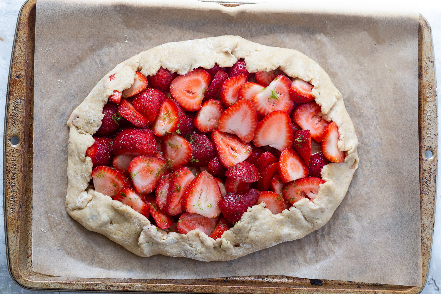 Strawberries on crust for our Vegan Strawberry Galette on parchment