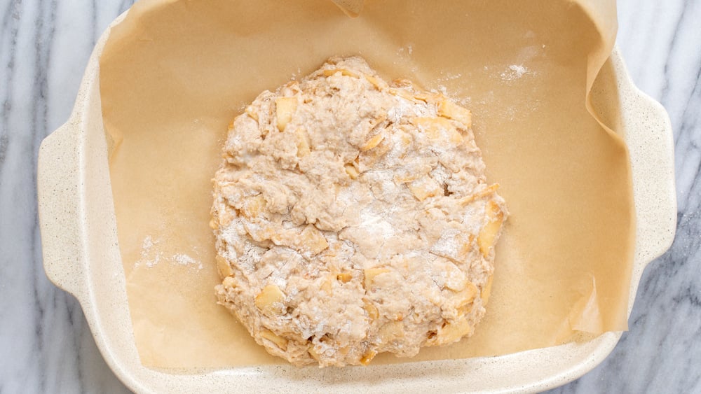 Dough for our Vegan Apple Cinnamon Scones in a parchment lined white baking dish