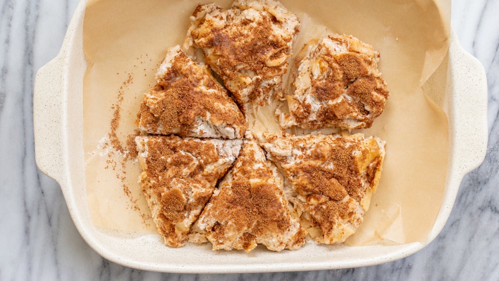 Sliced Scone Dough for our Vegan Apple Cinnamon Scones in a parchment lined white baking dish