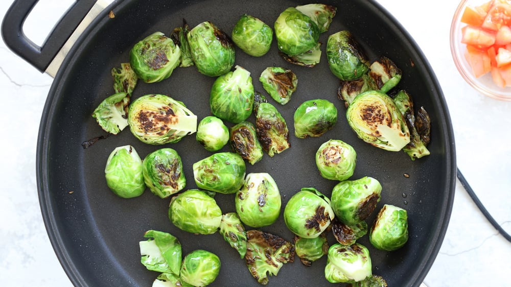 Brussels Sprouts caramelized in black skillet on stove top