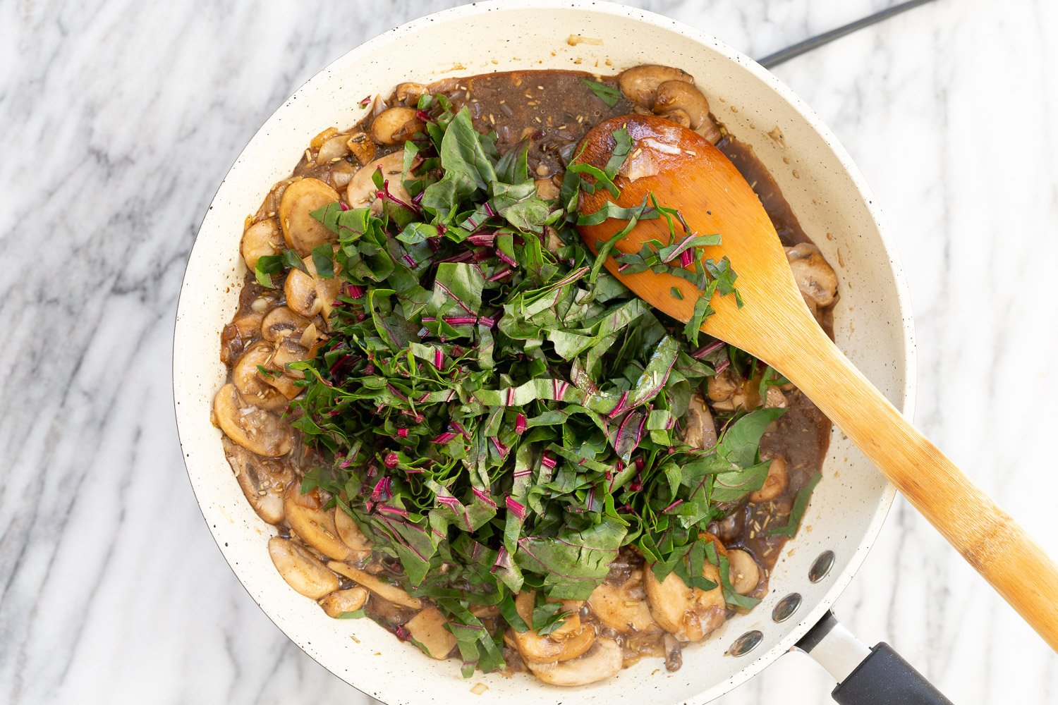 Chard added to the white skillet with our Mushroom Pot pie filling