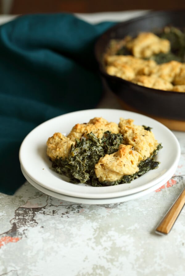 Vegan Creamed spinach in white plate and iron skillet