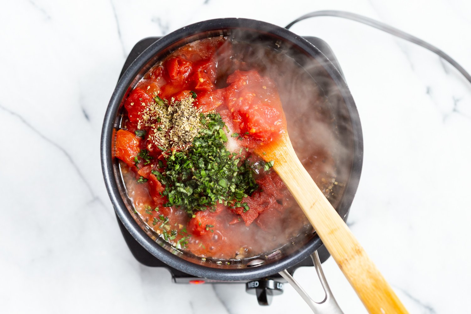 Ingredients for chunky marinara sauce in a black saucepan