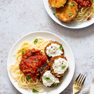 Vegan Eggplant Parmesan with spaghetti on white plates