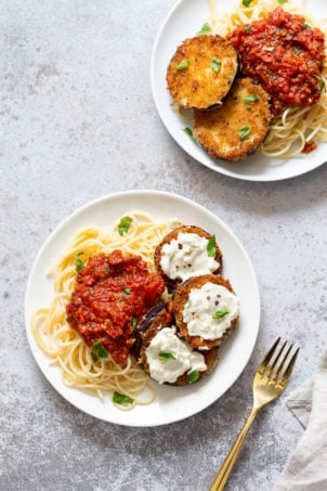 Vegan Eggplant Parmesan with spaghetti on white plates
