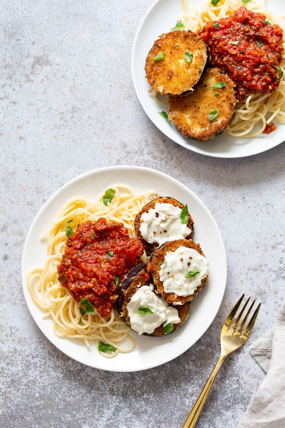 Vegan Eggplant Parmesan with spaghetti on white plates