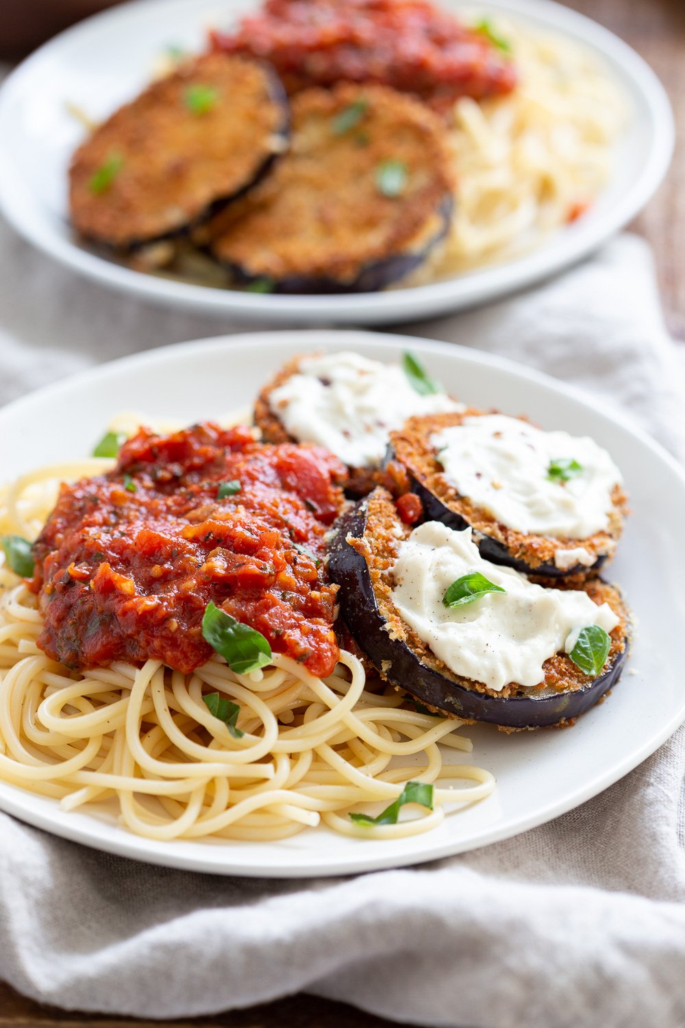 Vegan Eggplant Parmesan with spaghetti on white plates
