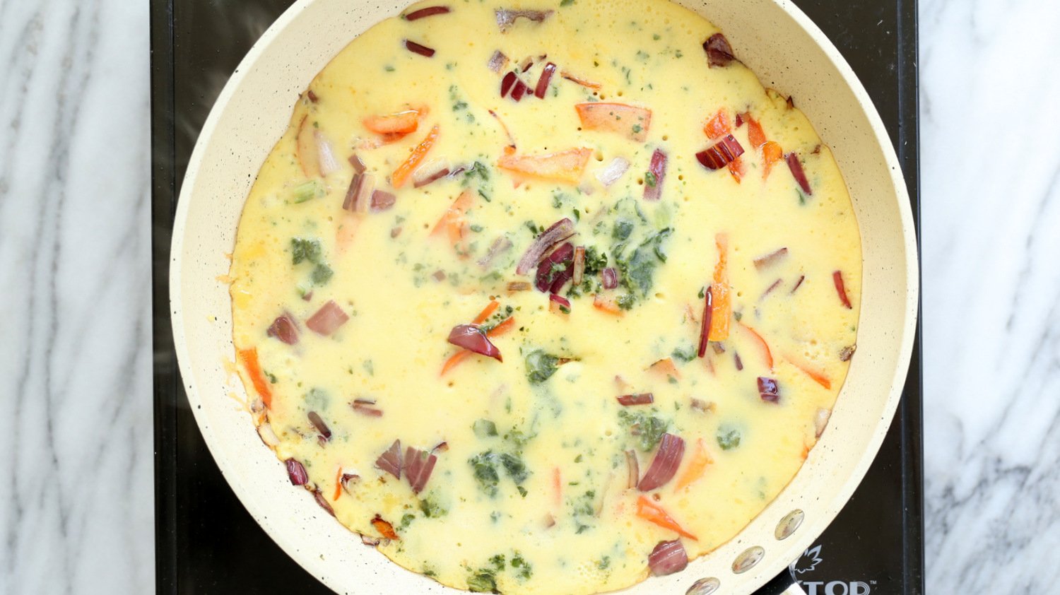 Veggie filled Vegan Omelet on a wite skillet