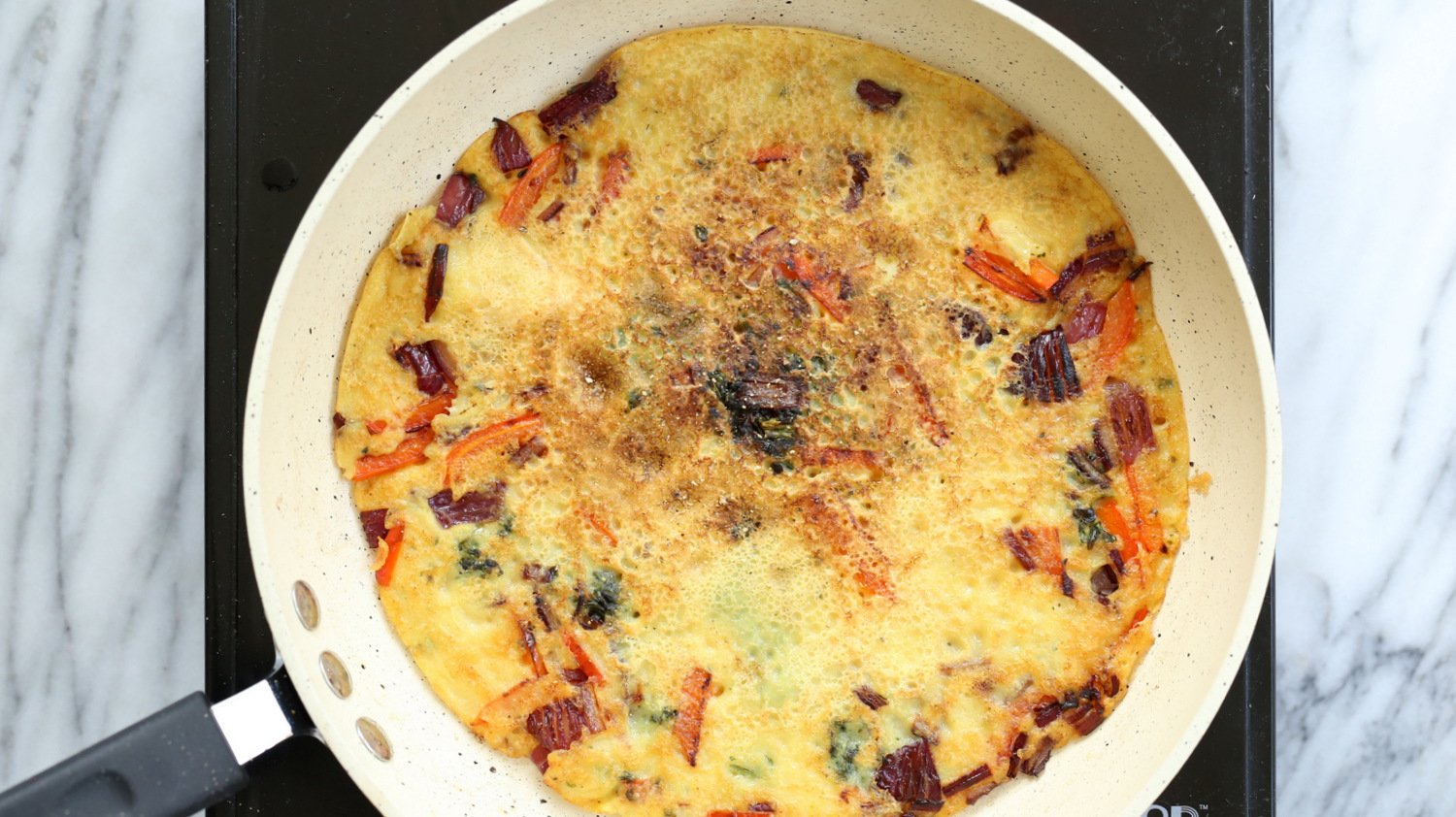 Veggie filled Vegan Omelet on a wite skillet