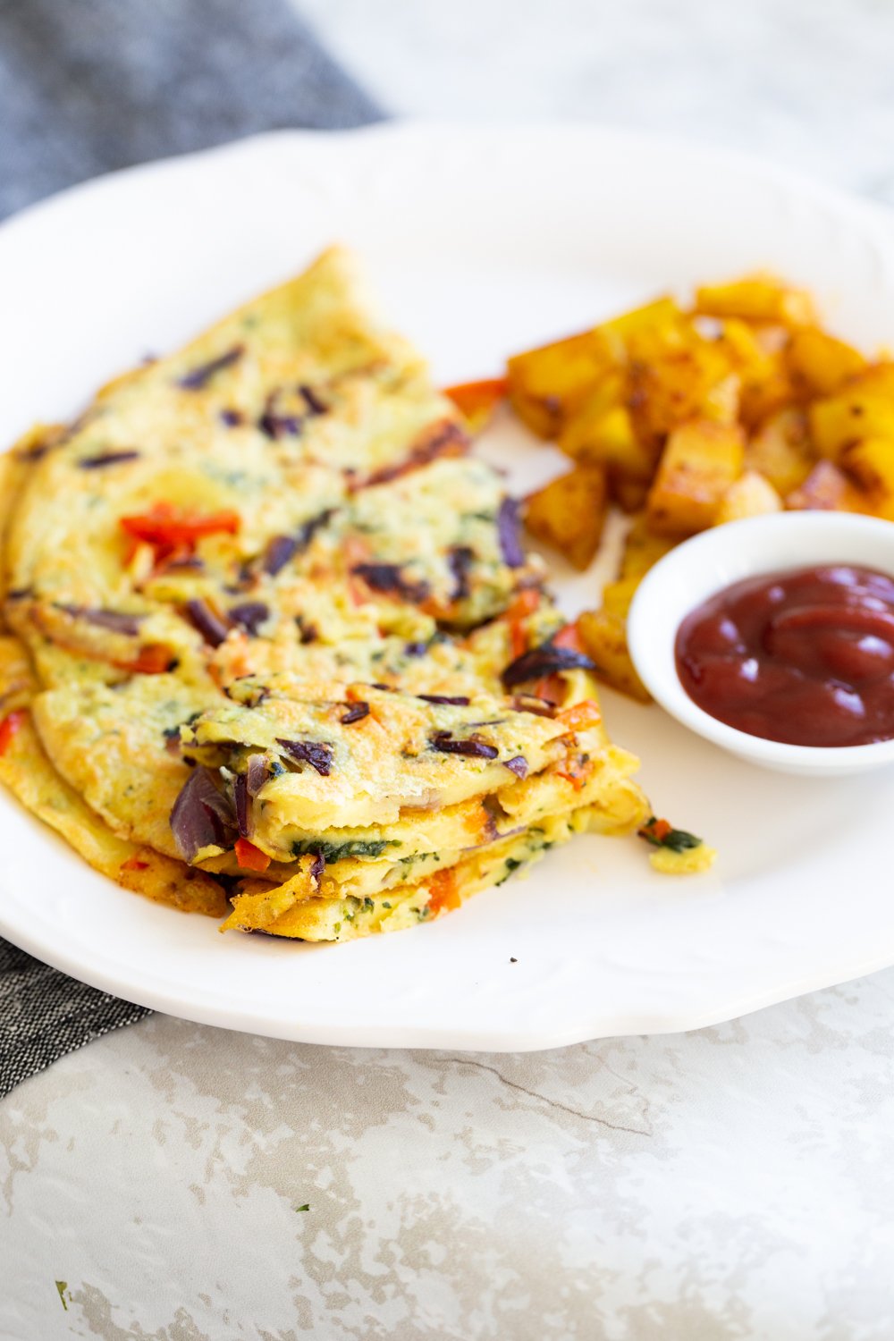 Veggie Vegan Omelet on a white plate with potatoes and ketchup