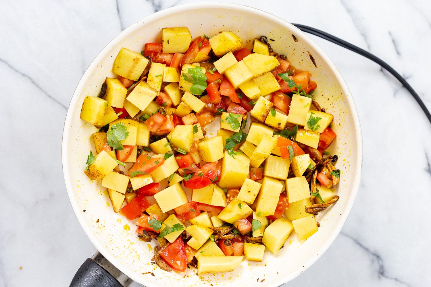 Potatoes and tomatoes in white skillet